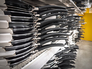 Rows of nonstick pancake pans with long black handles arranged on supermarket shelves. The perspective shows a cookware display, highlighting Teflon coated skillets and consumer choice in the kitchen 