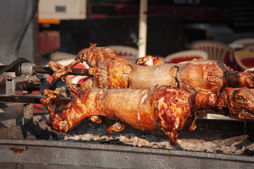 Whole lambs roast on a rotating skewer over charcoal at a Serbian market called Pecenje in serbian. cooking gives crisp skin and smoky flavor, reflecting traditional Balkan cuisine.