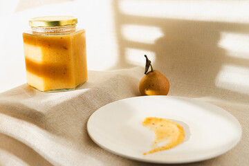 Homemade pear jam in a glass jar, surrounded by fresh pears, captures the essence of preserving...