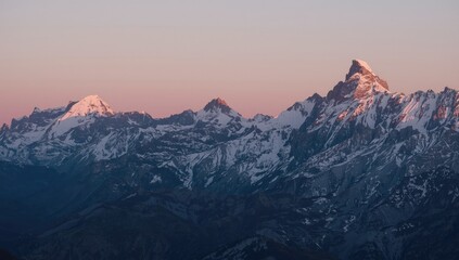 Majestic snow capped mountain peaks bathed in the soft glow of a serene sunrise or sunset sky