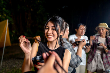 Indonesian southeast asian people are enjoying a meal, using chopsticks to serve themselves a barbecue meal from small black bowls. The scene of the lifestyle of enjoying food in a natural setting