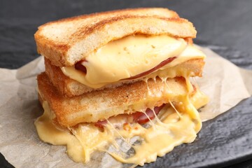 Tasty sandwiches with melted cheese and ham on table, closeup
