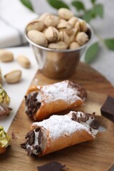 Delicious cannoli with ricotta cheese, pistachios, chocolate and powdered sugar on grey table, closeup
