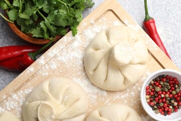 Uncooked khinkalis (dumplings) and spices on light table, flat lay