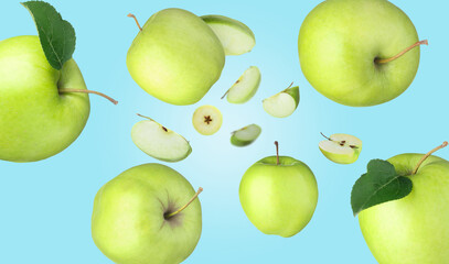 Fresh green apples swirling in air against light blue background