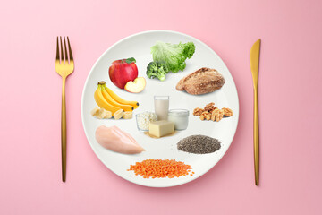 Plate with collection of different foods and cutlery on pink background, top view. Healthy eating