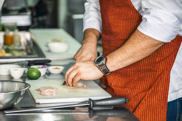 Unrecognizable chef preparing fish in a restaurant kitchen