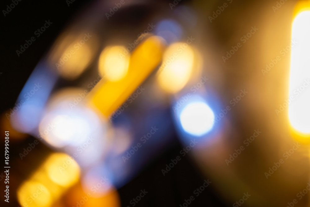 Poster abstract image showing blurred golden light with bokeh spheres against a dark background, creating a