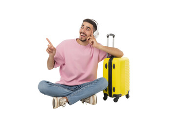 Happy young man with headphones by a suitcase, isolated, PNG