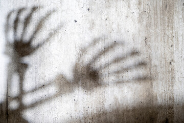 Abstract image of a skeleton hand shadow cast onto a grungy and aged cement surface. The texture...