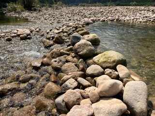 A Natural Rock Barrier Forms a Pathway Across a Shallow, Clear River in a Sunny Landscape