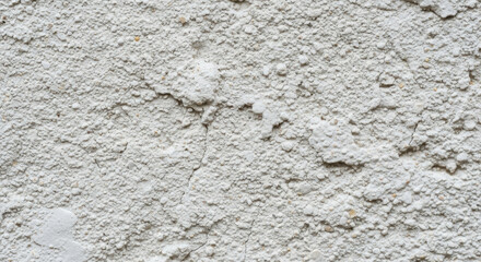 Close-up of a weathered, textured, light gray stucco wall.