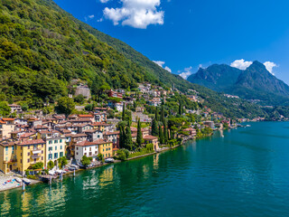 Fototapeta premium Lake Lugano, Italy. View of the lake, mountains and scenic village. A small Italian town by the lake on the boarder of Switzerland. Aerial drone view