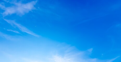 Vibrant blue sky with wispy clouds, a hint of a jet trail, and a soft gradient, creating a clean and serene natural background.