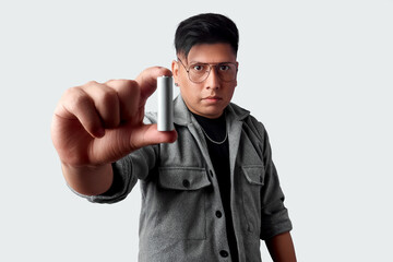Latino man presenting a single battery toward the viewer, representing reliable power, smart...