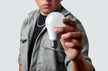 Latino man holding an LED bulb in front, conveying a bright idea, energy efficiency and smart home...