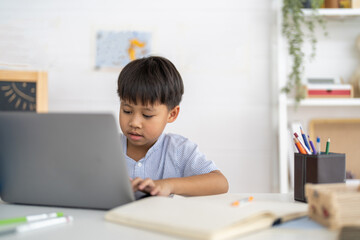 Asian boy using laptop with course online learning, distance education for kids, e-learning at home, child studying digital technology, interactive education platform, remote class tutorial