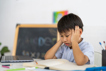 Asian boy stressed homework studying with hands on head, tired expression shows school pressure...