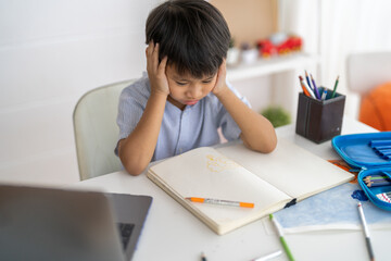 Asian boy stressed homework studying with hands on head, tired expression shows school pressure...