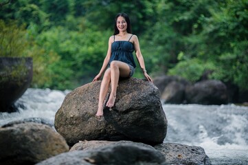 Serene Nature Escape: Young Woman by Stream in Lush Forest Setting