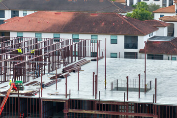 Construction site with hardhat workers assembling metal frame walls. Aerial view of large...