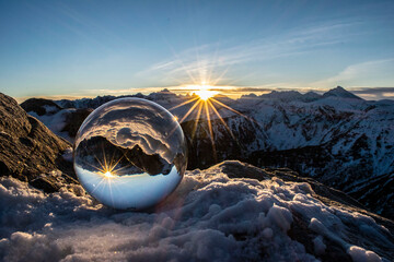 a crystal ball with reflecting sunlight surrounded by winter mountains