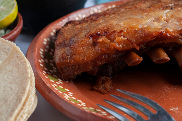Pork ribs on a mexican clay plate macro photography with a fork on the side