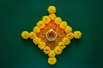 Clay diya lamp lits to celebrate for Diwali festival with colorful decoration marigold flowers on dark green background.