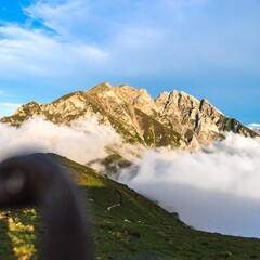 Majestic mountain peaks bathed in golden sunlight above a sea of clouds.