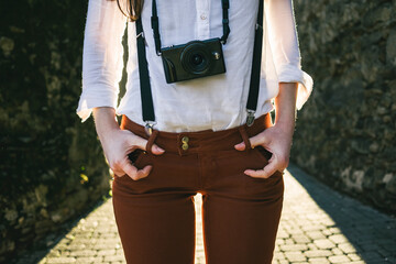 Woman wearing suspenders and camera around neck outdoors