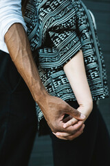 Closeup of interracial couple holding hands affectionately