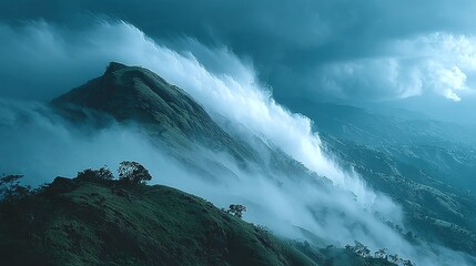 Fototapeta premium Mountain peak shrouded in mist under a cloudy blue sky.