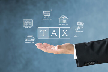 様々な税金のアイコンとTAXの文字を掲げるスーツを着た男性の手