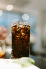 Refreshing soft drink in a glass with ice against a blurred background, offering a cool and...