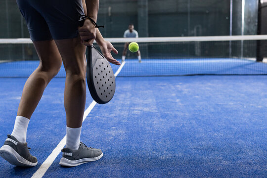 Diverse male opponents playing on blue court, serving ball with racket next to net, copy space