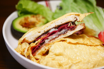 Delicious sandwich with avocado and fresh greens on a plate