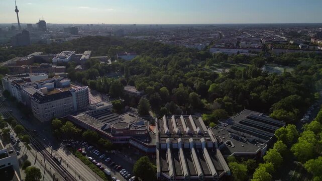 Sez and Volkspark Friedrichshain in Berlin, showcasing its lush greenery, a passing tram on a sunny day. Nice aerial view flight drone camera pointing down