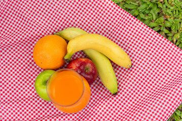 Picnic basket food bread fresh fruit coffee cup orange juice in wood wicker box on red Blanket. Wheat bakery fruit food and drinks in green park outdoor lifestyle. Breakfast healthy appetizer box.
