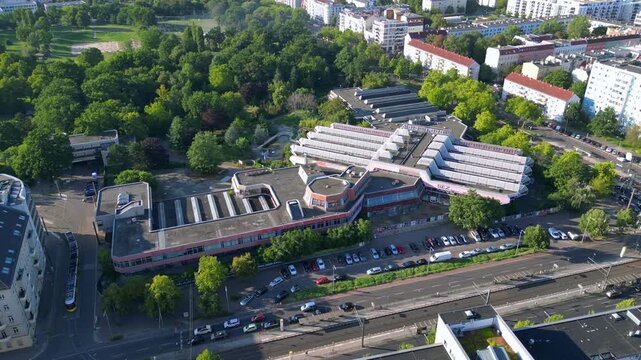 Sez and Volkspark Friedrichshain in Berlin, showcasing its lush greenery, a passing tram on a sunny day. Smooth aerial view flight circle drone footage