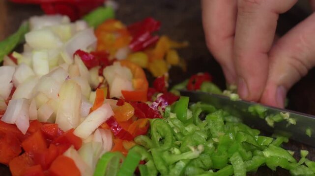 Close-up of a hand skillfully chopping a variety of fresh, colorful vegetables for an authentic Latin American recipe