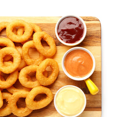 Wooden board with fried breaded onion rings and different sauces on white background