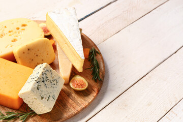 Plate with tasty cheese on white wooden background