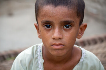 Close-up portrait of poor boy with sad eyes, emotional child face showing innocence and struggle