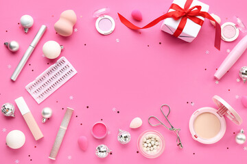 Frame made of different makeup products and Christmas decor on pink background