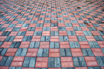 Paving stone surface featuring a pattern of red and gray bricks. The interlocking brick arrangement...