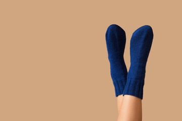 Legs of young woman in warm blue socks on beige background