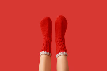 Legs of young woman in warm knitted socks on red background