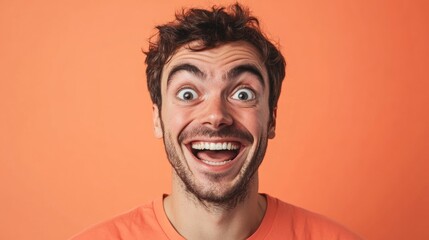 Man with an excited expression and wide eyes against an orange background showing pure joy and surprise portrait