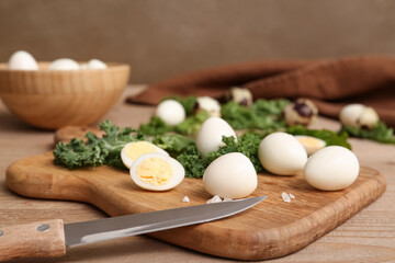 Board with fresh boiled quail eggs and lettuce on wooden table