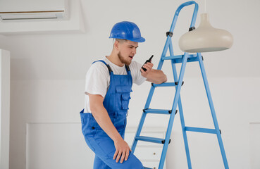 Male contractor talking on radio transmitter in room